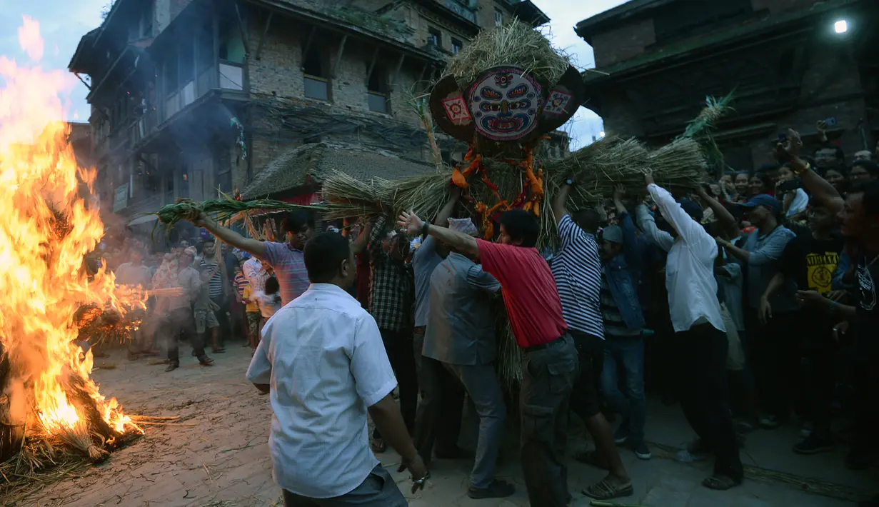 Para lelaki Nepal membawa patung jerami iblis Ghantakarna untuk dibakar dalam festival Ghantakarna di kota kuno Bhaktapur, Nepal (30/7/2019). Festival Hindu ini juga dikenal dengan nama Gathemangal. (AFP Photo/Prakash Mathema)