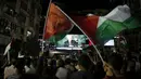 Warga Palestina mengibarkan bendera mereka saat menonton pidato Presiden Palestina, Mahmud Abbas di layar raksasa, Rabu (30/9). Sidang majelis Umum PBB menyetujui untuk mengibarkan bendera Palestina dan Vatikan. (AFP PHOTO/ ABBAS Momani)
