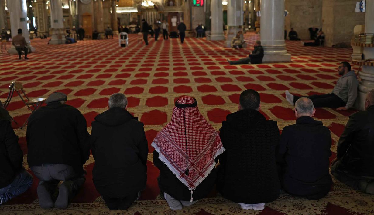 Di dalam bangunan, terdapat area luas di sekeliling Batu Sakhrah yang sering digunakan jamaah untuk duduk bersimpuh dan membaca Al-Quran. Tampak dalam foto, para pria Palestina berdoa di dalam Masjid Kubah Batu di kompleks Masjid al-Aqsa, Yerusalem menjelang waktu berbuka puasa selama bulan suci Ramadan 1447 Hijriah pada Rabu 25 Februari 2026. (AHMAD GHARABLI/AFP)