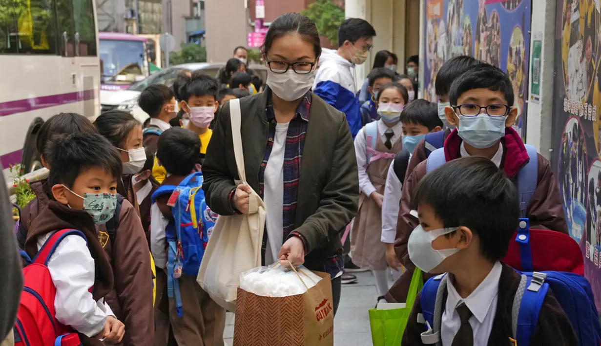 Siswa sekolah dasar mengantre untuk masuk bus sekolah di Hong Kong, Selasa (11/1/2022). Sekolah akan tutup mulai hari Jumat dan sampai setidaknya liburan Tahun Baru Imlek pada minggu pertama bulan Februari. (AP Photo/Kin Cheung)