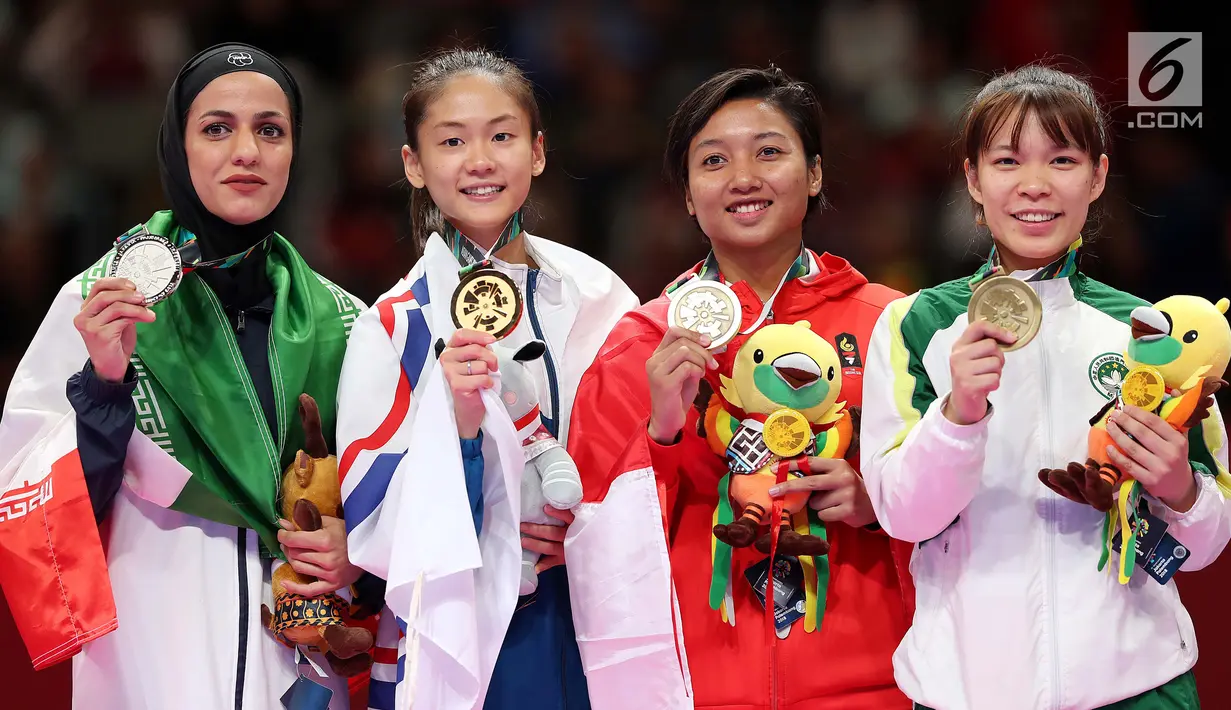 Karateka putri Indonesia, Cokorda Istri Agung Sanistyarani (kedua kanan) menunjukkan medali perunggu usai memenangkan pertandingan di babak final nomor Kumite 55 kg di Arena Karate JCC Senayan, Jakarta, Minggu (26/8). (Liputan6.com/Fery Pradolo)