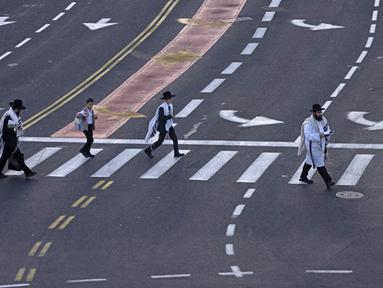 Orang-orang Yahudi ultraortodoks melintasi jalan raya bebas mobil saat warga Israel merayakan puasa Yom Kippur dan tidak mengemudi, Yerusalem, 4 Oktober 2022. Yom Kippur yang juga dikenal sebagai Hari Penebusan adalah salah satu hari libur terpenting Yahudi di mana orang Israel menjalankan puasa, refleksi, dan doa selama 25 jam. (MENAHEM KAHANA/AFP)