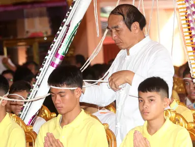 Pelatih tim sepak bola remaja Thailand, Ekkapol Janthawong (tengah) bersama anak asuhnya mengikuti ritual di Distrik Mae Sai, Chiang Rai, Kamis (19/7). Ritual ini diyakini memperpanjang hidup serta membersihkan mereka dari bahaya. (AP Photo/Sakchai Lalit)