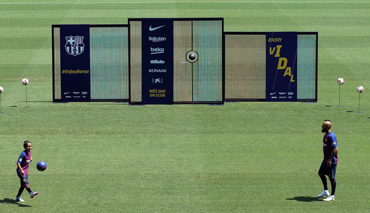 Pemain baru Barcelona, Arturo Vidal dan putranya Alonso Vidal menunjukkan skill bermain bola selama presentasi dirinya di stadion Camp Nou, Spanyol, (6/8). Vidal resmi diboyong Barcelona dengan kontrak selama tiga tahun. (AP Photo/Manu Fernandez)