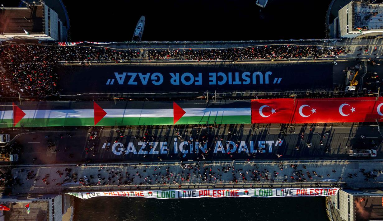 Foto udara menunjukkan ribuan orang yang berdemonstrasi menunjukkan solidaritas mereka dengan rakyat Palestina di tengah perang yang sedang berlangsung antara Israel dan kelompok Hamas di wilayah Gaza, di Jembatan Galata, Istanbul, Turki pada 1 Januari 2026. Ratusan ribu orang berkumpul di Jembatan Galata, Istanbul, Turki, melakukan aksi solidaritas besar-besaran bagi rakyat Palestina di Gaza. (Yasin AKGUL/AFP)