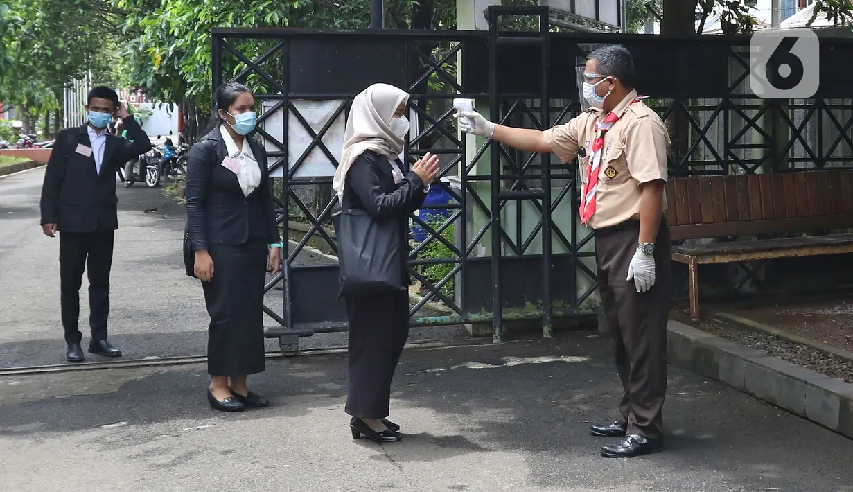 Sejumlah murid dicek suhu sebelum memasuki sekolah di SMKN 51, Jakarta, Rabu (7/4/2021). SMKN 51 melakukan uji coba masuk sekolah dan Uji Sertifikasi Kompetensi (USK) dengan protokol kesehatan yang ketat. (Liputan6.com/Herman Zakharia)