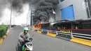 Pengendara ojek online melintasi bus polisi yang terbakar di dekat Flyover Slipi, Palmerah, Jakarta Barat, Rabu (22/5/2019). Belum diketahui penyebab terbakarnya dua bus yang terparkir bersama bus polisi lainnya dilokasi tersebut. (merdeka.com/Arie Basuki)
