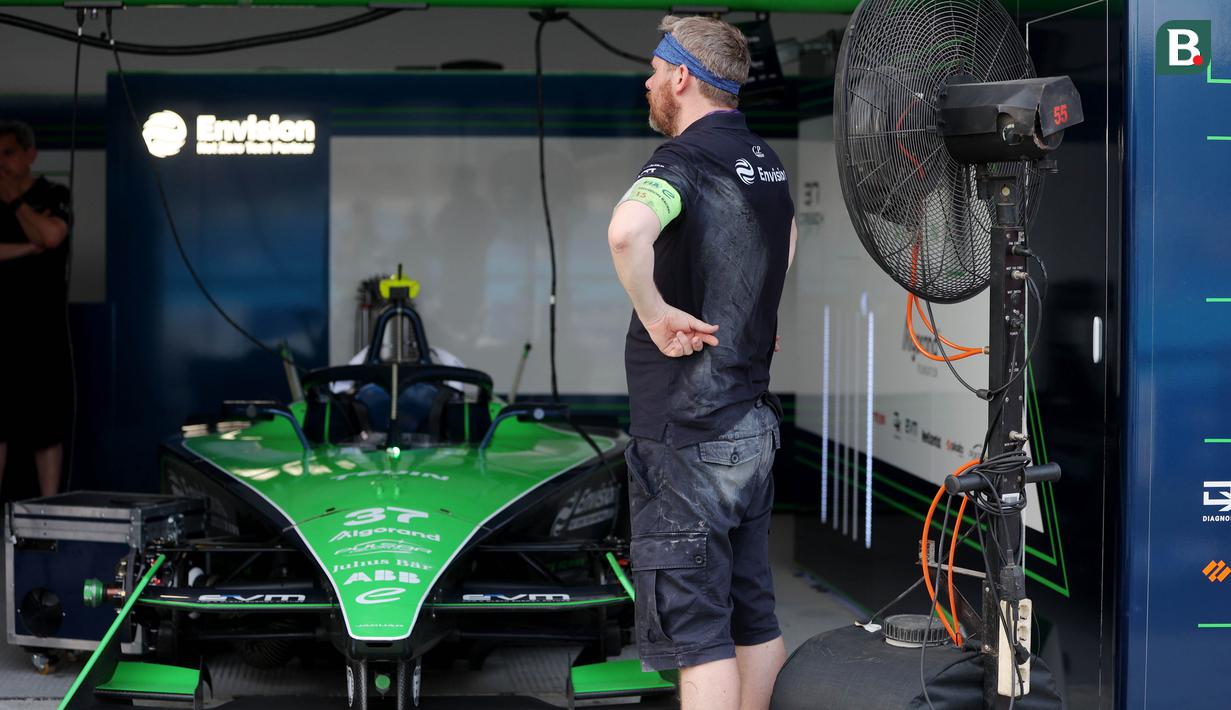 Kru paddock Envision Racing rehat sejenak di depan kipas angin saat mempersiapkan mobil jelang balapan Formula E di Sirkuit International E-Prix Circuit (JIEC), Ancol, Jakarta, Jumat (02/06/2023). (Bola.com/M Iqbal Ichsan)