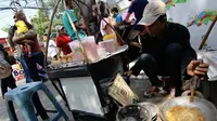 Salah satu penjual kerak telor tampak sedang membuatkan pesanan bagi pembeli (Liputan6.com/Faizal Fanani)