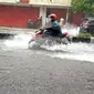 Seorang pengendara motor melintas di Jalan Basuki Rahmat Kota Malang yang tergenang air saat hujan lebat mengguyur (Liputan6.com/Zainul Arifin(