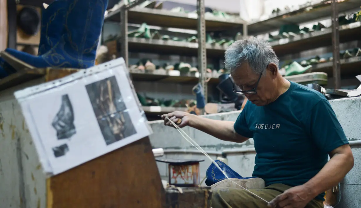 Seorang pengrajin mengerjakan sepasang sepatu bot kulit untuk pasar Amerika Serikat (AS) di bengkel Tegep Boots, Bandung, Jawa Barat pada 15 Juli 2025. (Timur MATAHARI/AFP)