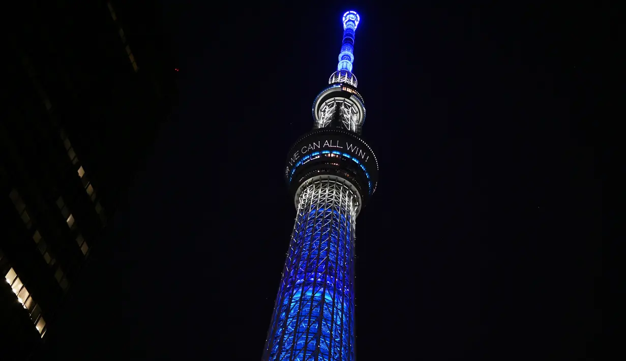 Menara Tokyo Skytree terlihat menyala dengan warna biru bertuliskan "Bersama Kita Semua Bisa Menang" di Tokyo, 5 April 2020. Ungkapan dukungan dan pesan harapan tersebut muncul di tengah merebaknya pandemi virus corona Covid-19. (CHARLY TRIBALLEAU/AFP)