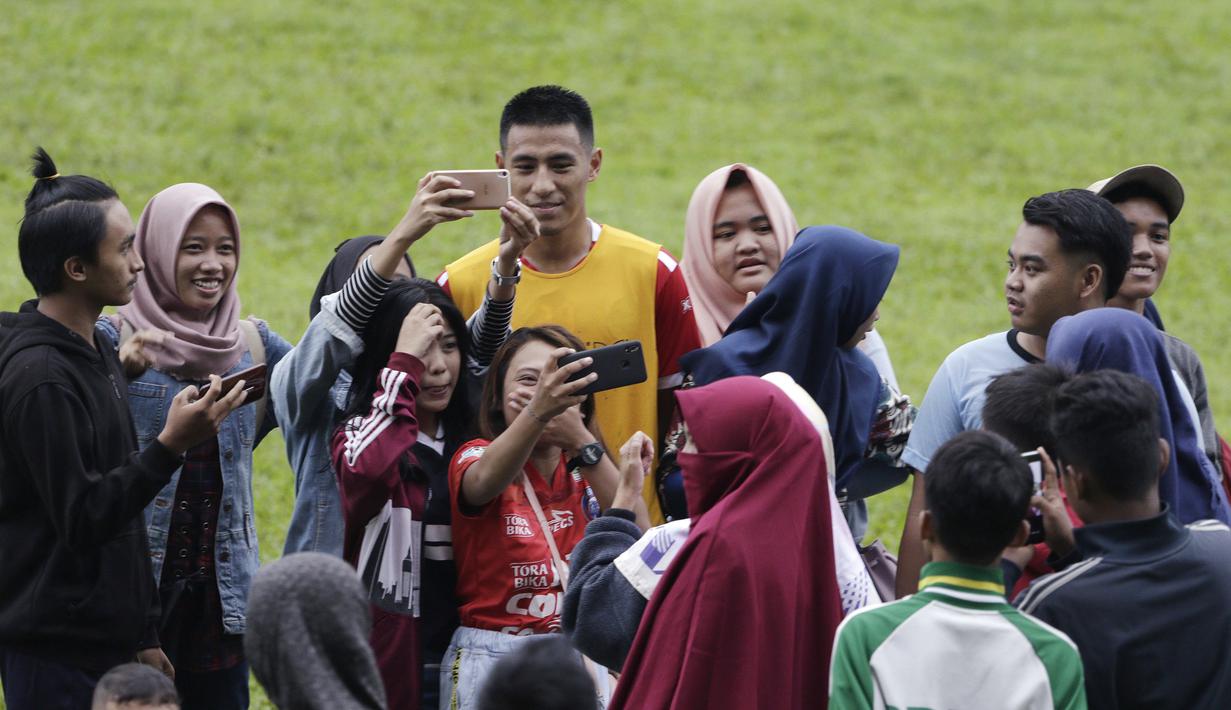 Pemain Arema FC, Hanif Sjahbandi, foto bersama dengan fans usai sesi latihan di Stadion Gajayana, Malang, Kamis (11/4). Setelah sesi latihan, pemain Arema FC melayani permintaan fans untuk foto bersama. (Bola.com/Yoppy Renato)