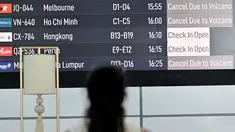Seorang penumpang melihat papan elektronik yang menampilkan pembatalan penerbangan setelah gunung berapi Lewotobi Laki-Laki meletus di Bandara Internasional Ngurah Rai di Tuban dekat Denpasar, Bali, pada 18 Juni 2025. (SONNY TUMBELAKA/AFP)