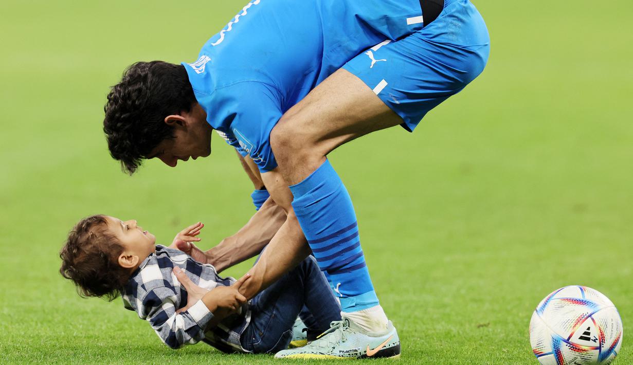 Pemain Maroko, Sofiane Boufal, merayakan kemenangan atas Portugal bersama anaknya pada laga perempat final di Stadion Al-Thumama, Sabtu (10/12/2022). (AFP/Kari Jaafar)