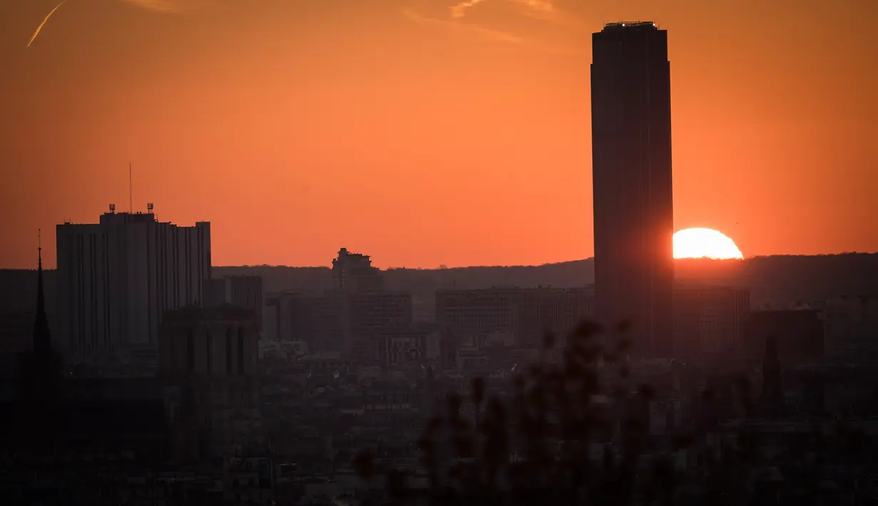 Kawasanan Montparnasse saat matahari terbenam dengan diselimuti kabut polusi, Paris, Prancis (3/12). Untuk mengurangi polusi ini, petugas setempat akan mengeluarkan kebijakan sirkulasi lalu lintas alternatif. (AFP/Lionel Bonaventure)