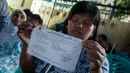 Seorang wanita menunjukan lembaran data pemilih saat akan menggunakan hak pilihya dalam Pilkada Putaran kedua di TPS 07 Kelurahan Cawang, Jakarta, Rabu (19/4). (Liputan6.com/Gempur M. Surya)