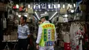 Seorang pria mengenakan rompi saat mengiklankan pakaian, sepatu, dan tas di luar sebuah toko di pasar Namdaemun di Seoul (2/7/2019). Dibangun pada tahun 1946, Pasar Namdaemun merupakan salah satu pasar tradisional yang terbesar di Korea. (AFP Photo/Minji Suh)