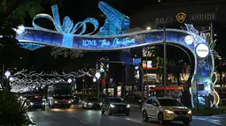 Kendaraan melintas di sepanjang distrik perbelanjaan utama Singapura di Orchard Road yang dihiasi lampu Natal pada Selasa (8/12/2020). Mengusung tema Love This Christmas, acara tahun ini lebih sunyi karena aktivitas jalanan dibatasi di tengah pandemi Covid-19. (ROSLAN RAHMAN / AFP)