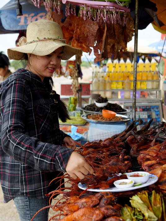 Pedagang menyiapkan tikus bakar untuk pelanggannya di provinsi Battambang, Kamboja (8/8/2019). Tikus bakar yang lebih besar dijual dengan harga 1,25 USD atau sekitar 17000 ribu rupiah. (AFP Photo/Tang Chhin Sotthy)