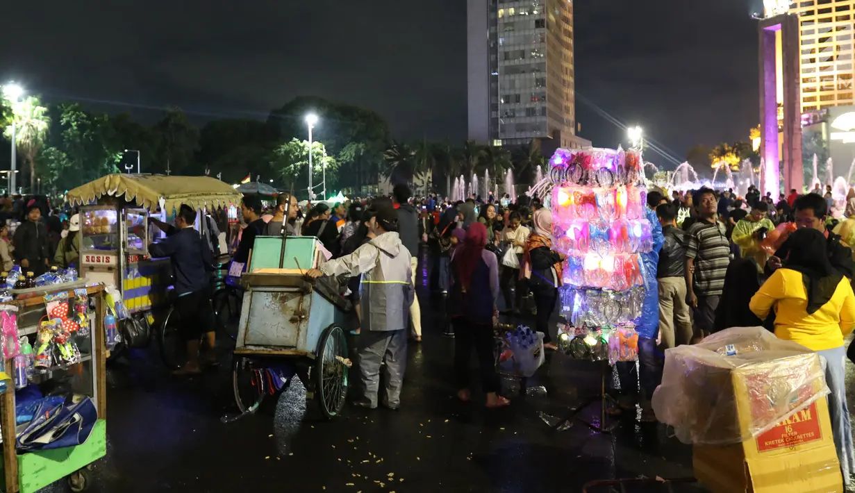 Pedagang menjual terompet, balon dan makanan pada malam pergantian tahun di kawasan Bundaran HI, Jakarta, Senin (31/12). Pergantian tahun dimanfaatkan pedagang untuk mencari keuntungan dengan berjualan pernak pernik tahun baru.(Liputan6.com/Angga Yuniar)