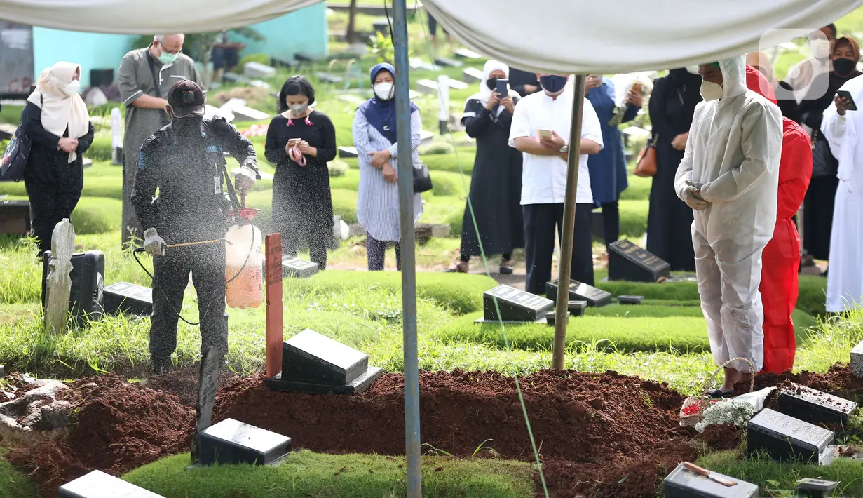 Petugas menyemprotkan cairan disinfektan pada makam presenter Rina Gunawan saat prosesi pemakaman di TPU Tanah Kusir, Jakarta, Rabu (3/3/2021). Pemakaman Rina Gunawan dihadiri oleh keluarga dan sahabat dekat. (Kapanlagi.com/Budy Santoso)
