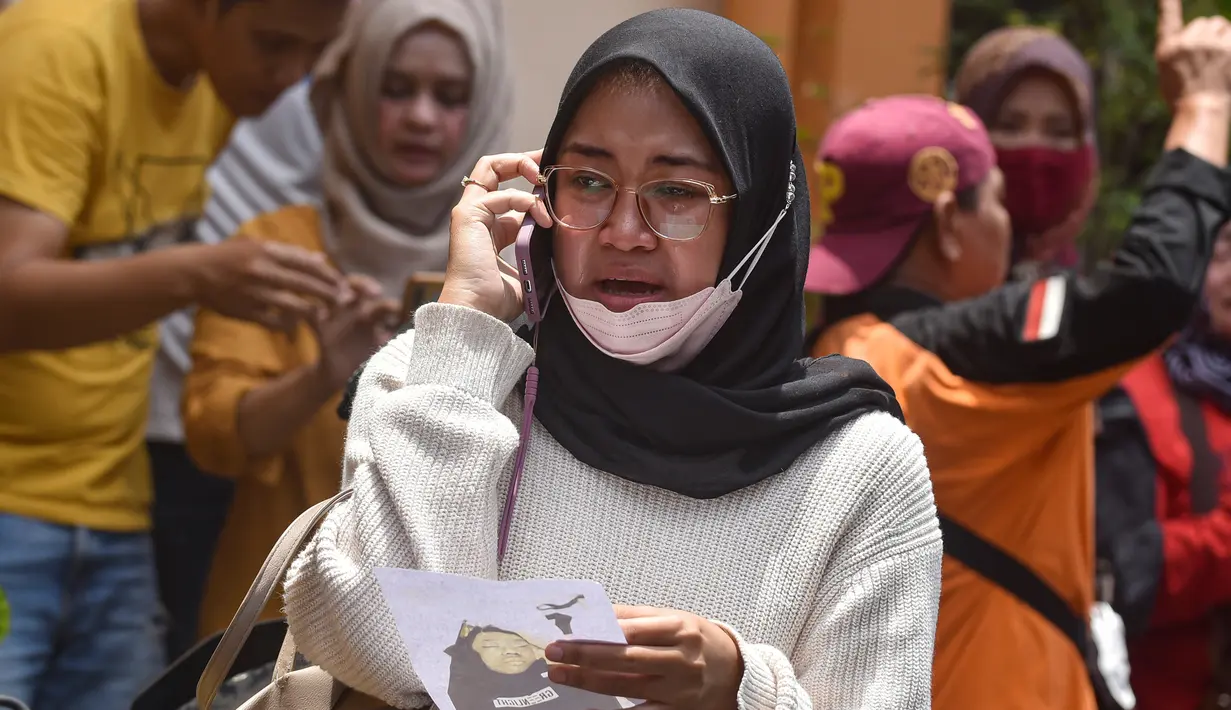 Seorang wanita melakukan panggilan telepon sambil memegang foto korban kerusuhan Stadion Kanjuruhan menangis saat menunggu di Rumah Sakit Saiful Anwar, Malang, Jawa Timur, Minggu (2/10/2022). Hingga saat ini, dilaporkan sebanyak 129 orang meninggal dunia dalam kejadian tersebut. (AP Photo/Trisnadi)