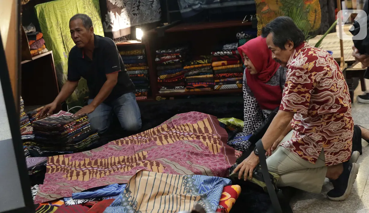 Pengunjung memilih koleksi batik yang dipamerkan pada Interior and Craft (ICRA) Exhibition 2019 yang dihelat di Hall A Jakarta Convention Center (JCC), Senayan, Jakarta, Minggu (6/10/2019). Ratusan motif batik dari berbagai daerah dipamerkan pada ajang ini. (Liputan6.com/Helmi Fithriansyah)