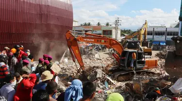 Eskavator membantu mengangkat puing bangunan yang runtuh akibat gempa di Pasar Meureudu, Pidie Jaya, Aceh, Kamis (8/12). Dikabarkan korban meninggal sudah mencapai 102 orang. (Liputan6.com/Angga Yuniar)