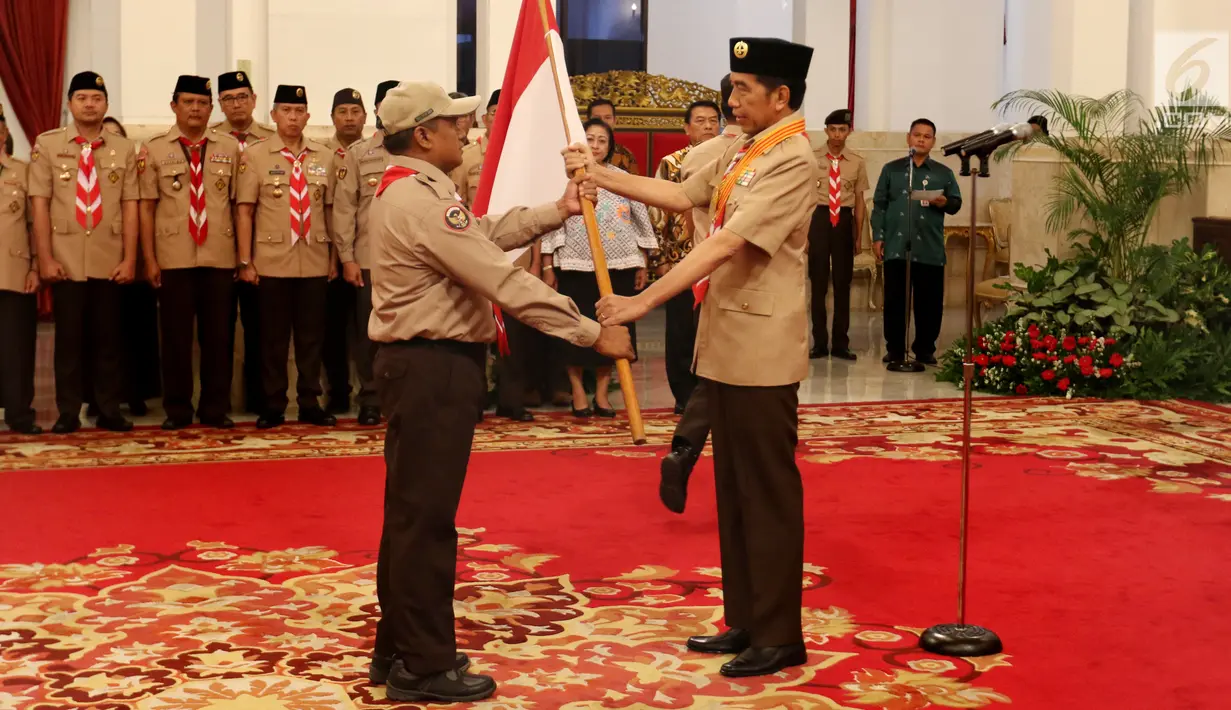 Presiden Joko Widodo (kanan) memberikan bendera Merah Putih kepada Kontingen Gerakan Pramuka Indonesia saat upacara pelepasan di Istana Negara, Jakarta, Jumat (19/7/2019). Pramuka Indonesia akan terbang ke Virginia Barat untuk menghadiri Jambore Pramuka Dunia XXIV. (Liputan6.com/Angga Yuniar)