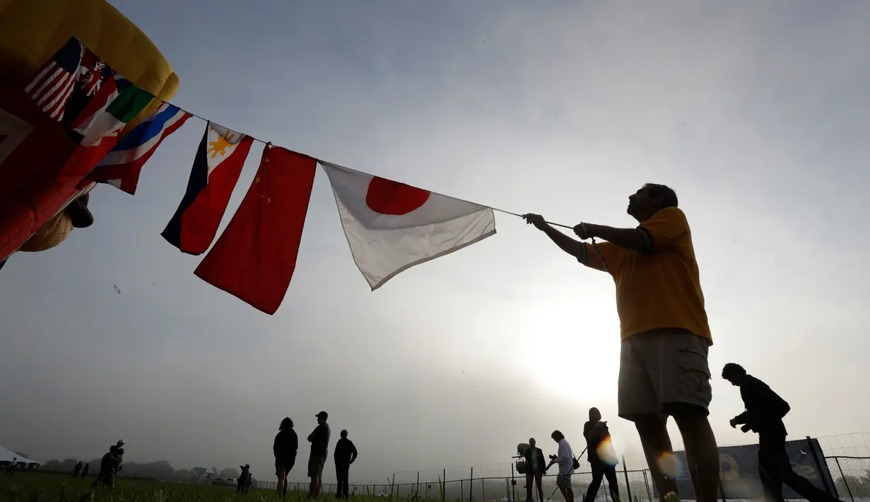 Seorang peserta mengikatkan bendera dari berbagai negara di balon udaranya sebelum mengikuti Festival QuickChek New Jersey di Kota Readington, New Jersey (28/7). (AP Photo/Julio Cortez)