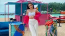 Nicole Parham kali ini berpose di samping tong besar di pantai mengenakan crop top putih dan jaket merah, gaya foto ini membuatnya terlihat seksi. (Instagram/ nicoleparham_)