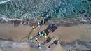 Peserta kursus selancar memasuki air saat menantang hawa dingin di Lofoten Islands, Norwegia, (10/3/2018). Suhu udara minus 13°C dan suhu diatas air sekitar 4°C. (AFP/Oliver Morin)