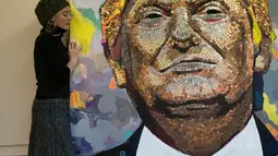 Seniman Ukraina Daria Marchenko berpose disamping lukisan Presiden AS Donald Trump di Akademi St George di New York (30/1). Lukisan ini dibuat dengan menggunakan dari sen dolar AS, nickels dan dimes. (AFP Photo/Don Emmert)