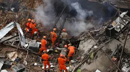 Petugas pemadam kebakaran dan penyelamat saat berupaya membersihkan reruntuhan bangunan yang hancur akibat ledakan yang terjadi Rio de Janeiro, Brasil, Senin (19/10/2015). Peristiwa ini menewaskan 7 orang dan lainnya cedera. (REUTERS/Pilar Olivares)