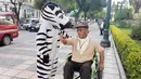 Warga berpakaian seperti zebra berbincang dengan seorang kakek penyandang disabilitas saat program pendidikan di jalan di La Paz, Bolivia,(5/12). (REUTERS/David Mercado)