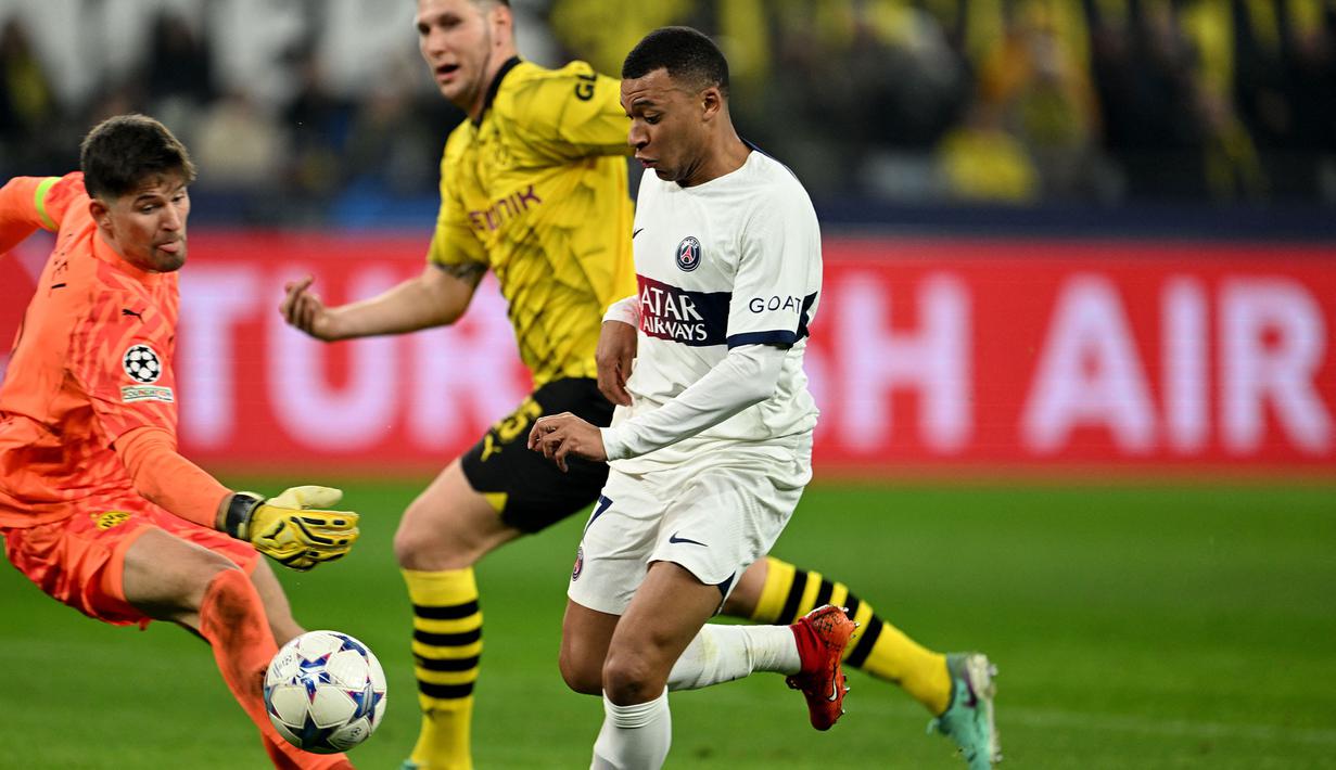 Pemain PSG, Kylian Mbappe (kanan) berusaha melewati kiper Borussia Dortmund, Gregor Kobel pada laga lanjutan Grup F Liga Champions 2023/2024 di Signal Iduna Park, Dortmund, Jerman, Kamis (14/12/2023) dini hari WIB. (AFP/Ina Fassbender)