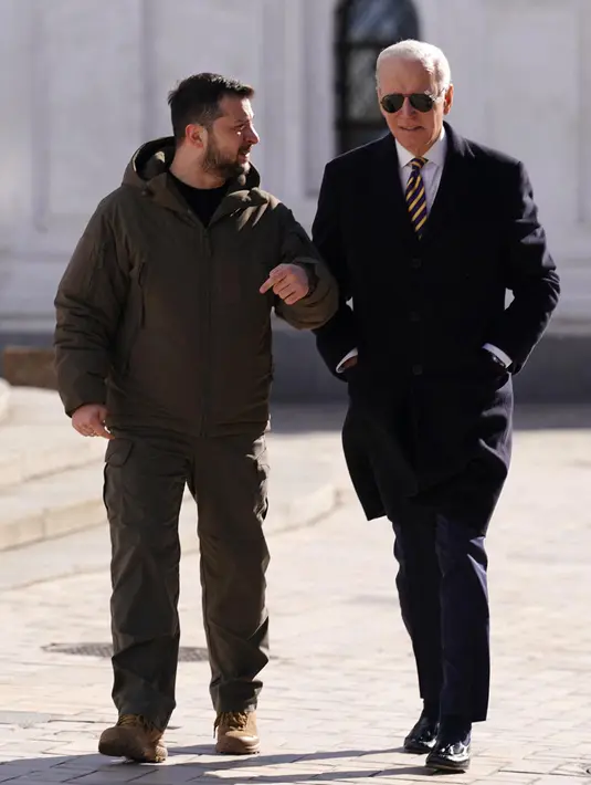 Presiden AS Joe Biden (kanan) berjalan di samping Presiden Ukraina Volodymyr Zelensky (kiri) saat tiba untuk kunjungan di Kyiv, Ukraina pada 20 Februari 2023. Presiden AS Joe Biden melakukan kunjungan mendadak ke Kyiv pada 20 Februari 2023, menjelang peringatan satu tahun invasi Rusia ke Ukraina. Biden bertemu dengan Presiden Ukraina Volodymyr Zelensky di ibu kota Ukraina dalam kunjungan pertamanya ke negara itu sejak dimulainya konflik. (Dimitar DILKOFF/AFP)