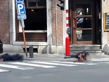 Seorang petugas polisi berdiri di lokasi dekat dua jenazah polisi korban penembakan di Liege, Belgia (29/5). Seorang pria menembak mati tiga orang di dekat sebuah kafe di Kota Liege, Belgia, Selasa waktu setempat. Dua di antara korban adalah polisi. (AP)