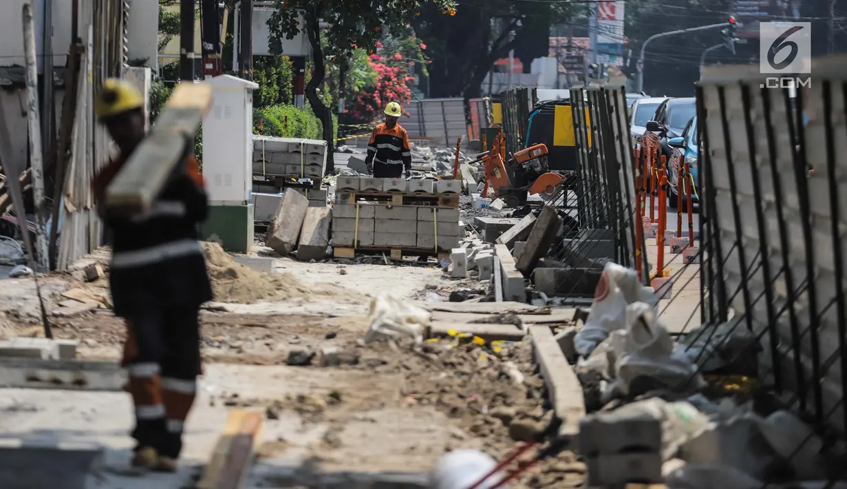 Pekerja menyelesaikan proyek revitaslisasi trotoar di kawasan Cikini, Jakarta, Senin (1/7/2019). Revitalisasi trotoar di kawasan Cikini hingga Kramat ditargetkan rampung pada Desember 2019. (Liputan6.com/Faizal Fanani)
