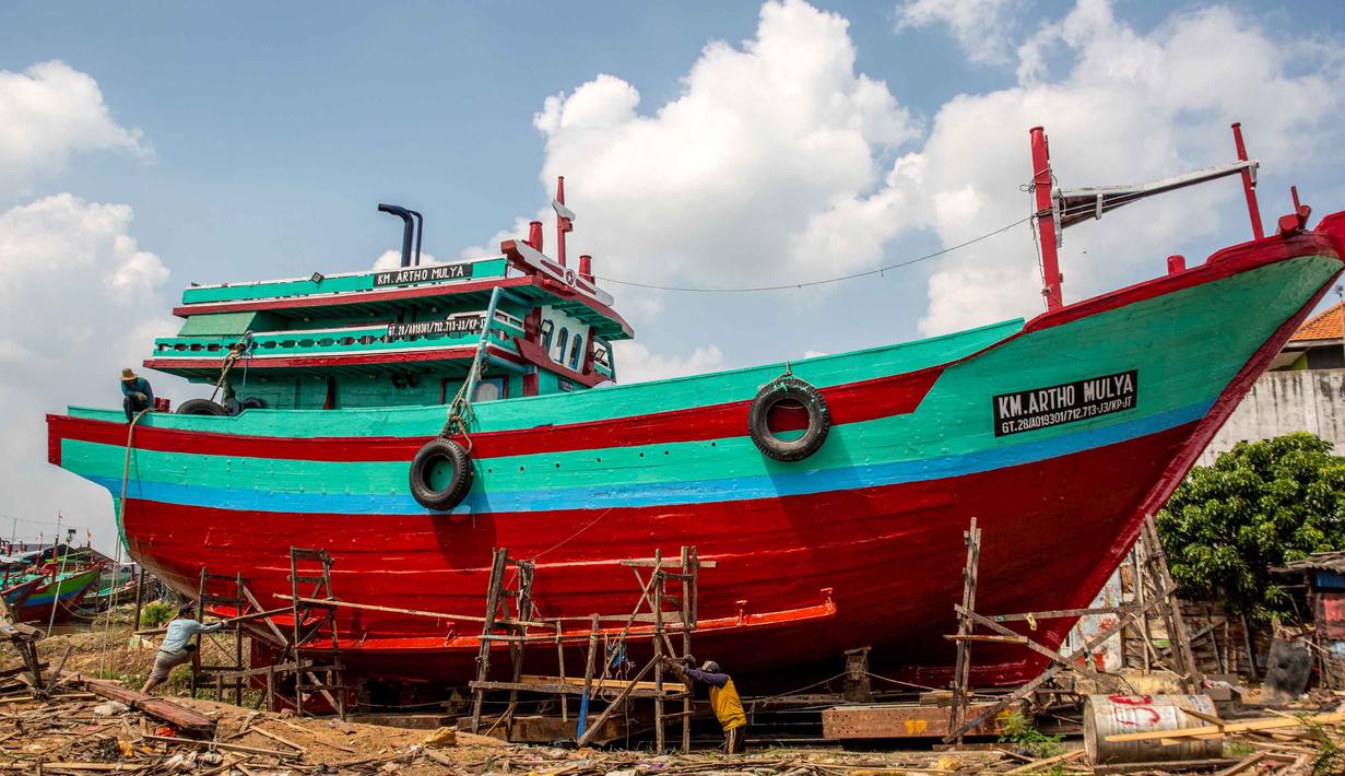 Nelayan menuntut pemerintah segera memberikan solusi, seperti penetapan harga BBM khusus, agar mereka bisa kembali melaut. Tampak dalam foto, para pria mengecat ulang perahu nelayan sementara kapal-kapal lain tetap berada di darat di Pelabuhan Juwana, Jawa Tengah, Rabu 6 Mei 2026. (Devi RAHMAN/AFP)