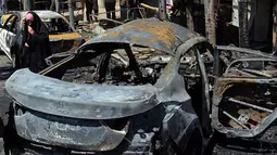 Bangkai mobil yang hangus terbakar usai terkena ledakan bom di Baghdad, Irak (30/5). Dalam insiden ini, pihak radikal ISIS mengklaim bahwa serangan bom bunuh diri tersebut dilakukan oleh kelompok mereka. (AP Photo / Karim Kadim)