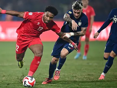 Pemain naturalisasi baru Vietnam, Nguyen Xuan Son (kiri) menggiring bola melewati pemain Thailand, Nicholas Mickelson dalam laga leg pertama final Piala AFF 2024 yang berlangsung di Viet Tri Stadium, Vietnam, Selasa (02/01/2025) waktu setempat. (AFP/Nhac Nguyen)