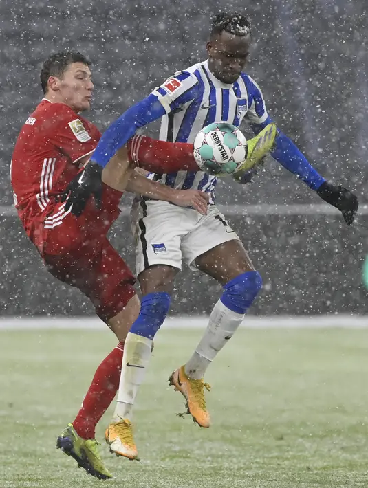Bek Bayern Munchen, Benjamin Pavard berebut bola dengan penyerang Hertha Berlin, Dodi Lukebakio dalam ajang Bundesliga 2020/2021 pekan 20 di Olympiastadion, Sabtu (6/2/2021) dini hari WIB. Bayern Munchen menang dengan skor tipis 1-0 saat bertemu Hertha Berlin. (John MacDougall/pool via AP)