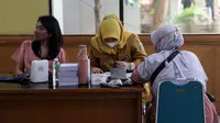 Petugas kesehatan mendata warga yang menjalani vaksinasi booster kedua atau dosis keempat di kawasan Kantor Wali Kota Jakarta Timur, Jakarta, Selasa (24/1/2023). Dimulainya vaksinasi booster kedua juga berdasarkan rekomendasi Komite Ahli Penasihat Ahli Imunisasi Nasional (IndonesiaTechnical Advisory Group on Immunization/ITAGI). (Liputan6.com/Johan Tallo)