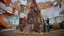 Mengangkat tema Terang dari Timur, dekorasi Pohon Natal pada tahun ini dihadirkan dengan nuansa Papua dan dapat dinikmati pengunjung hingga 31 Januari 2026 di ruang pameran Perpustakaan lantai 6 kampus PCU. Tampak dalam foto, salah satu mahasiswa memasang sentuhan akhir pada instalasi dekorasi berbentuk pohon Natal dengan motif budaya Papua di Perpustakaan Petra Christian University (PCU), Surabaya, Jawa Timur, Kamis 18 Desember 2025. (JUNI KRISWANTO/AFP)