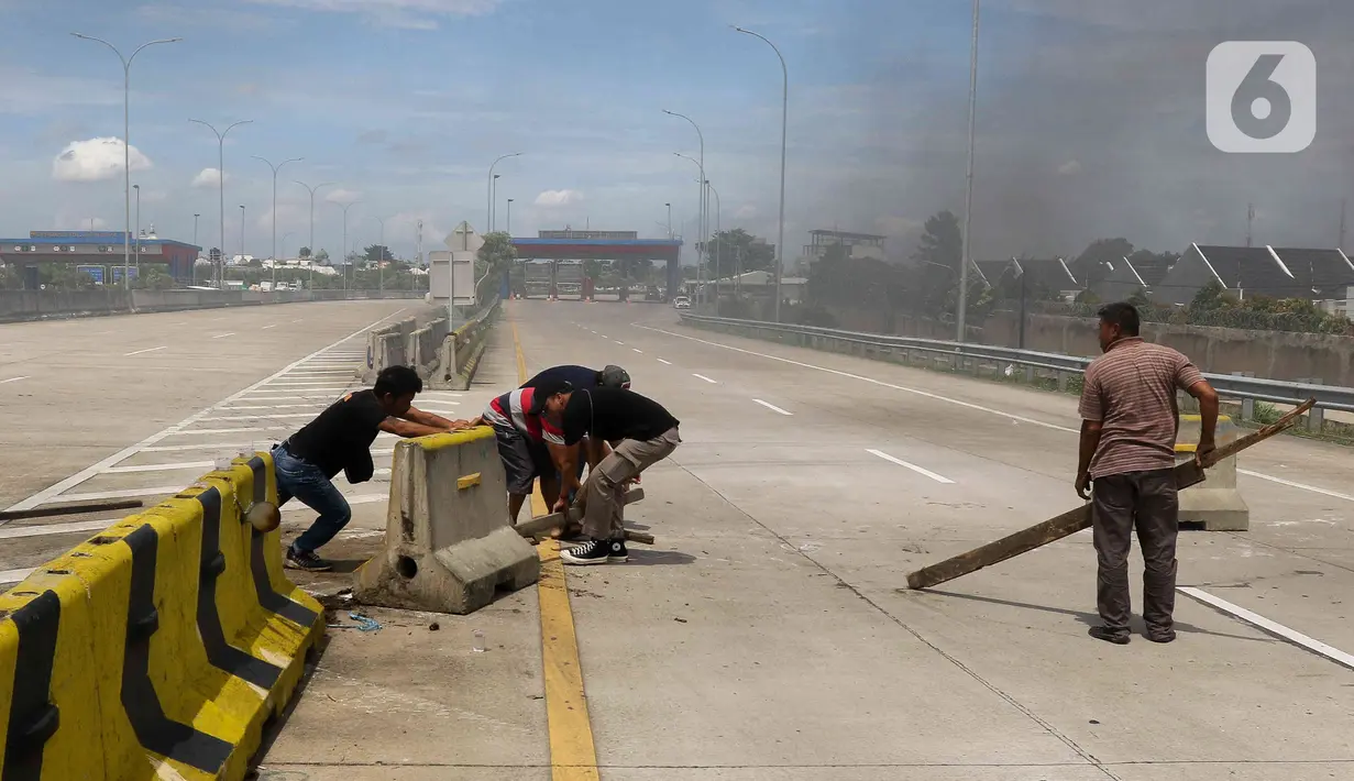 Warga melakukan aksi menutup akses jalan menuju Gerbang Tol (GT) Jatikarya 1& 2, di Jalan tol Cimanggis-Cibitung, Bekasi, Jawa Barat, Rabu (8/2/2023). Dalam aksinya mereka menuntut Pengadilan Negeri Kota Bekasi segera menyelesaikan pembayaran atas penggunaan tanah untuk tol seluas 4,2 hektar. (Liputan6.com/Herman Zakharia)
