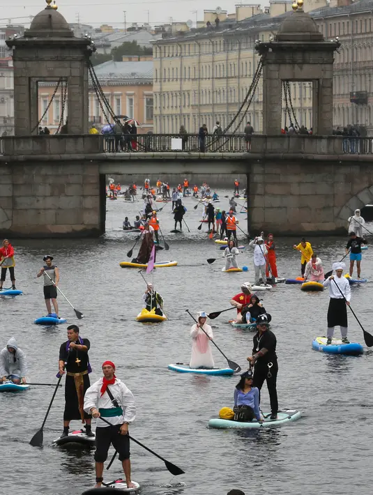 Orang-orang mengenakan kostum saat mendayung "paddle board" di Sungai Fontanka pada festival SUP (Stand Up Paddle)-Surfing di St.Petersburg, Rusia, Minggu (12/8). Dalam paddling, papan digerakkan dengan cara mendayung sambil berdiri. (AP/Dmitri Lovetsky)