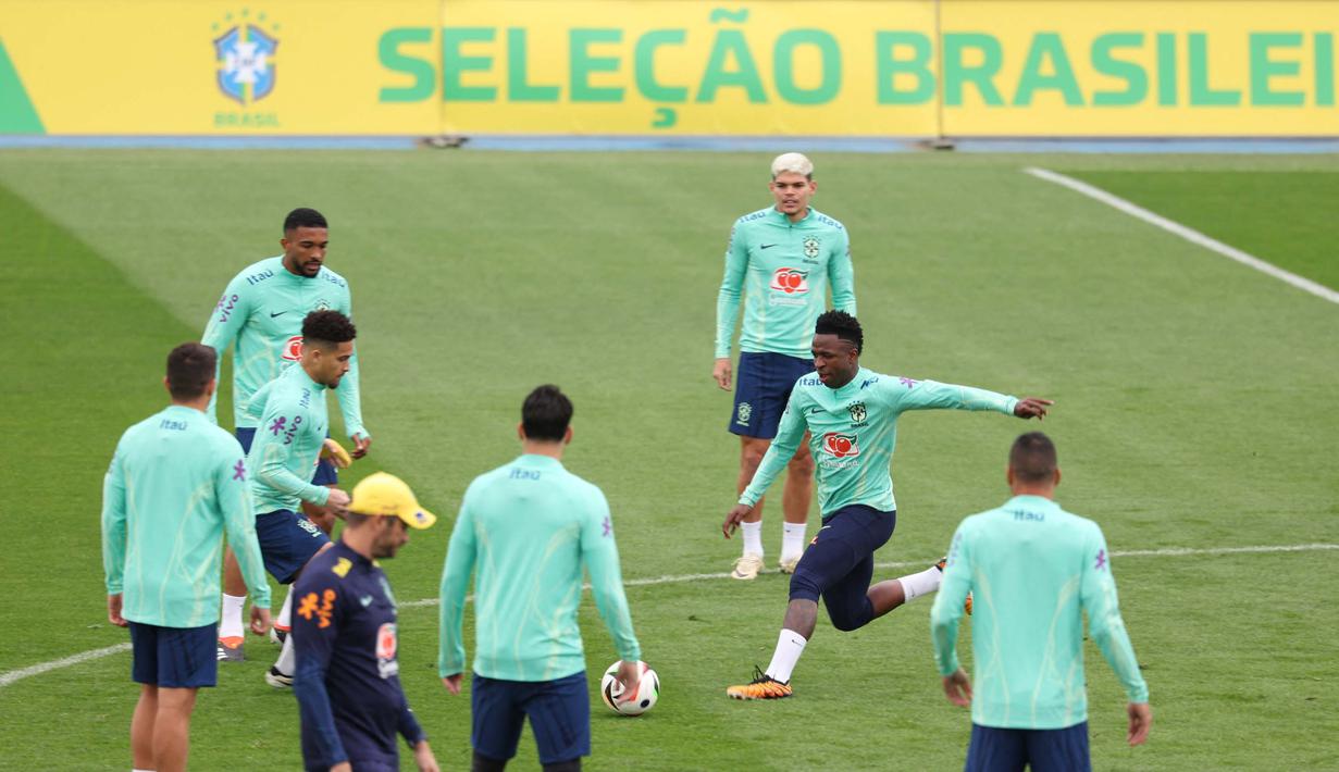 Penyerang Brasil, Vinicius Junior (kanan) bersama rekan setimnya menghadiri sesi latihan menjelang pertandingan sepak bola FIFA Matchday melawan Spanyol di tempat latihan Ciudad Real Madrid di Valdebebas pinggiran kota Madrid, pada tanggal 25 Maret 2024. (Pierre-Philippe MARCOU/AFP)