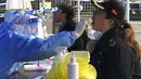 Seorang pekerja medis mengumpulkan sampel sampel swab dari penduduk di daerah penguncian di distrik Jingan di Shanghai barat (4/4/2022). Pengiriman petugas kesehetan untuk membasmi wabah COVID-19 yang menyebar dengan cepat di kota terbesar di China. (AP Photo/Chen Si)